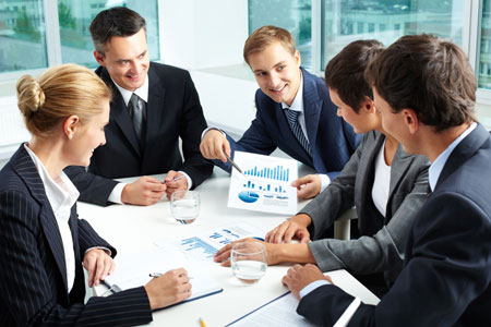 Professionals in a meeting smiling and discussing various charts